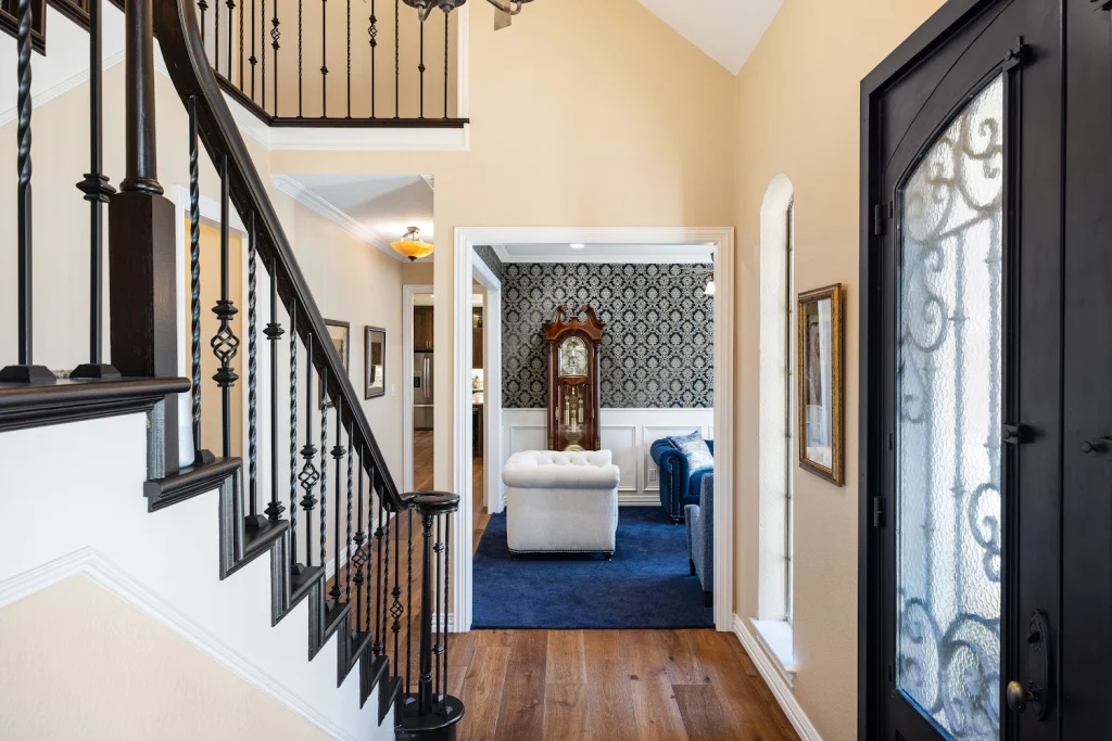 Elegant home interior with dark wood stairs, wrought iron railings, hardwood floors, and a living room